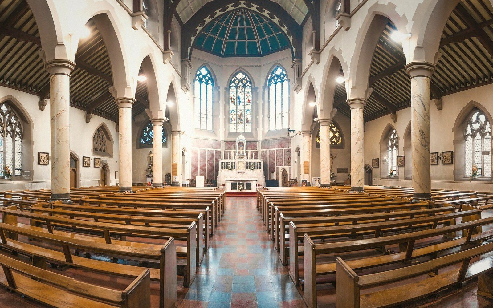 The nave of a university chapel, empty pews, stone columns, light falling from clerestory windows