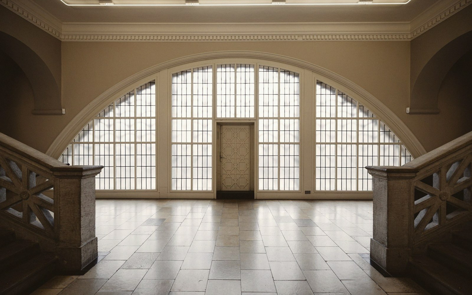 Arched hallway with tall grid-paned windows and a central ornate door
