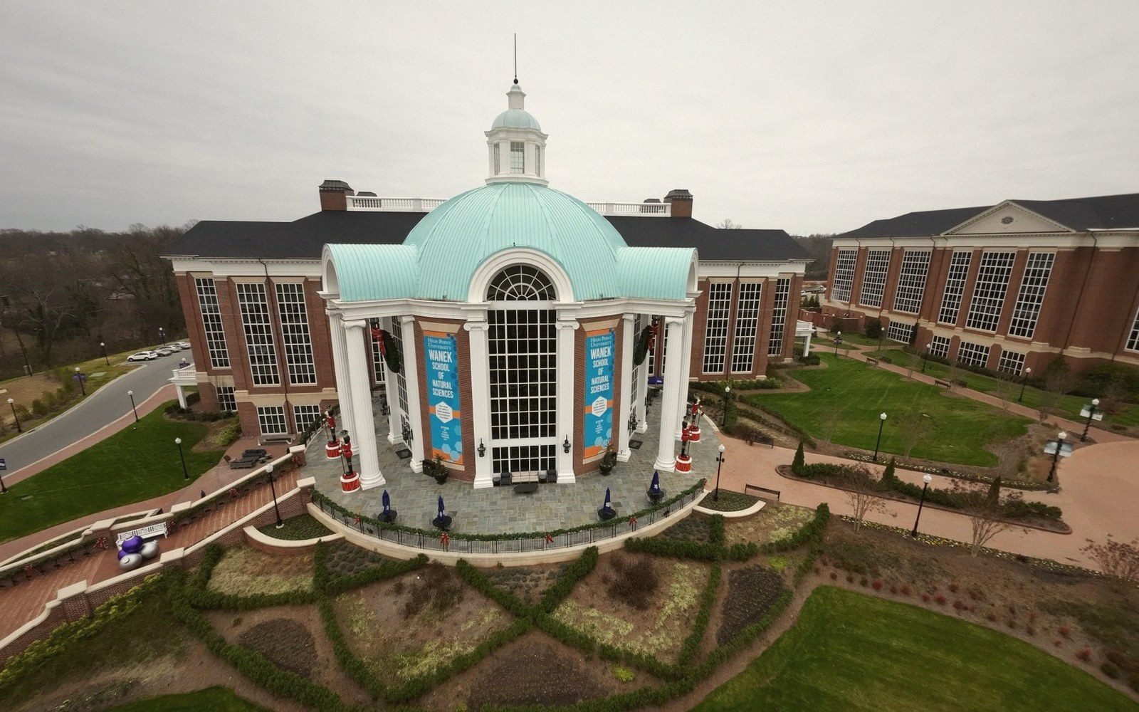 Aerial view of a domed brick building with columned entrance amid campus lawns and walkways