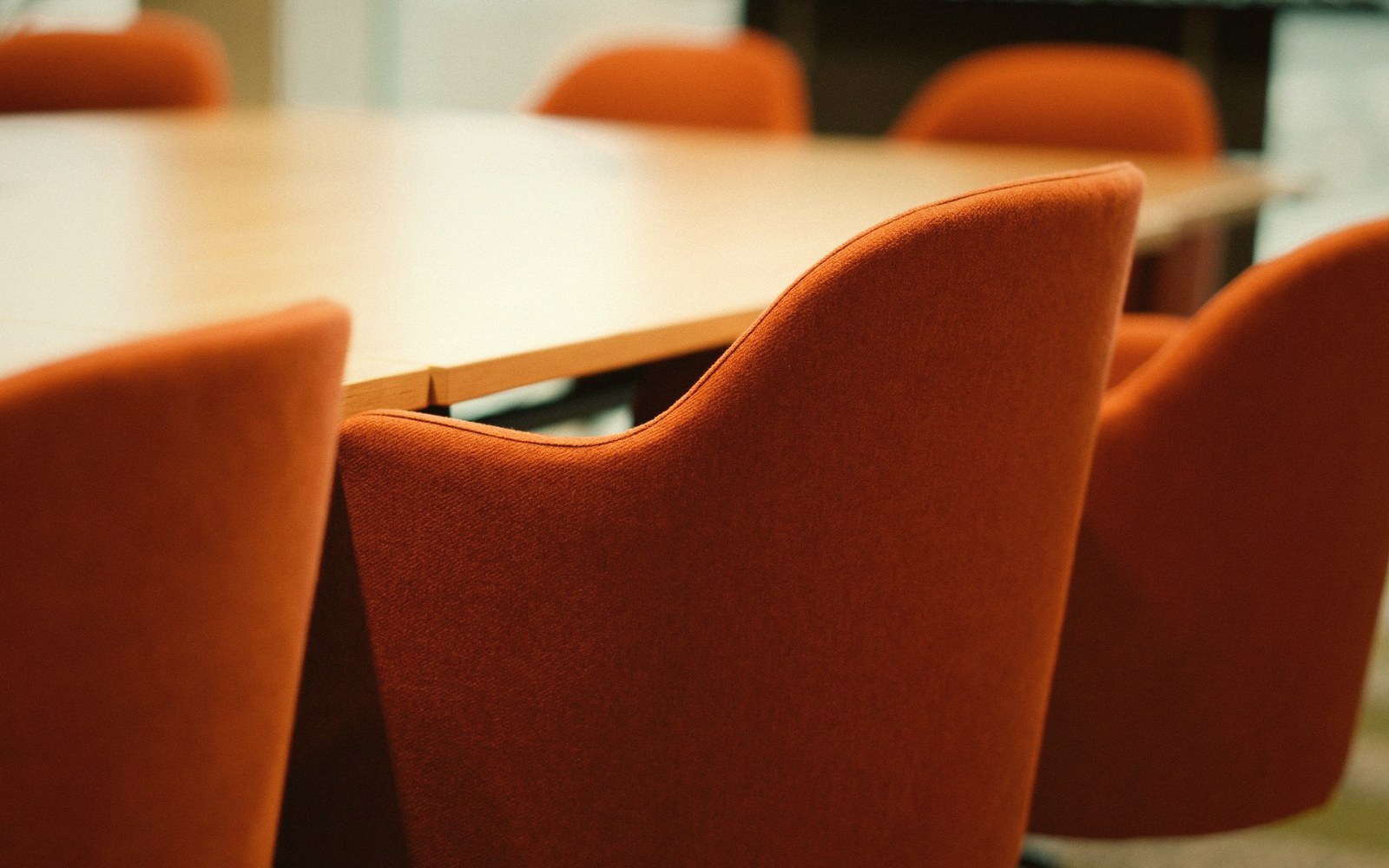 Orange upholstered chairs surround an oval conference table
